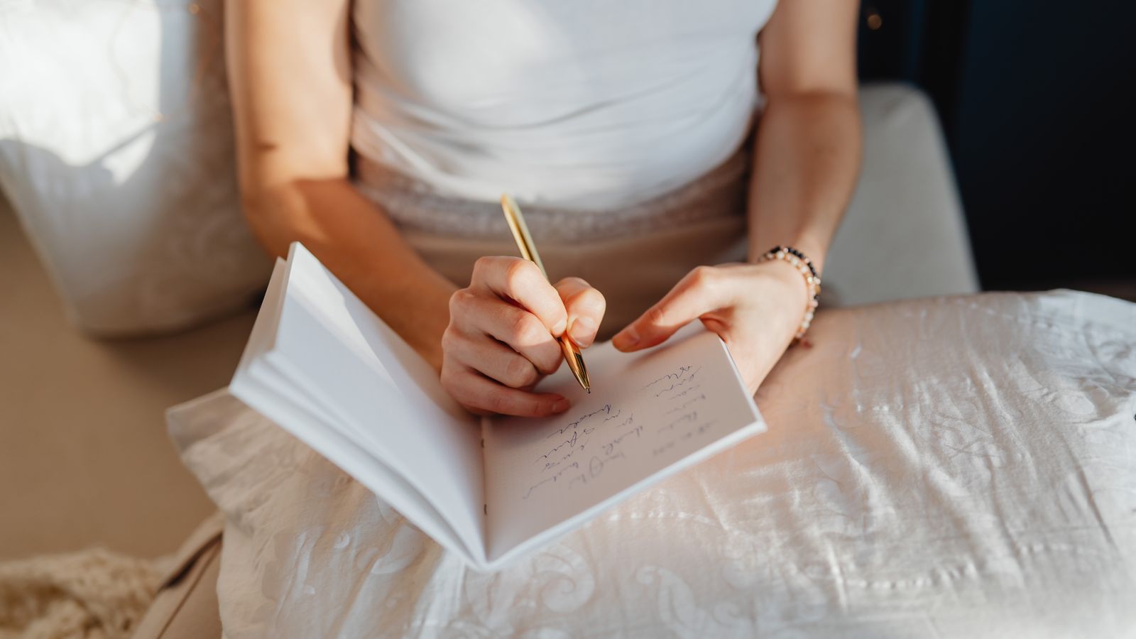 A woman writing in a notebook while sitting comfortably indoors
