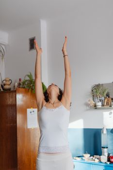 A woman in a cozy home setting practices morning stretching exercises for relaxation and self-care.