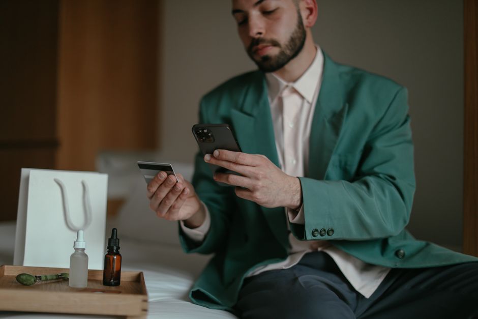Young woman shopping online using a smartphone and credit card indoors.