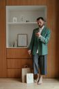 Man in Green Suit Standing Beside Brown Wooden Cabinet