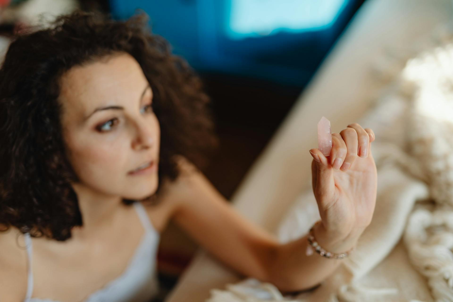 Focused woman holding a healing crystal indoors, embodying relaxation and alternative medicine.