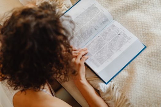Overhead view of a woman reading a book with a focus on relaxation and leisure.