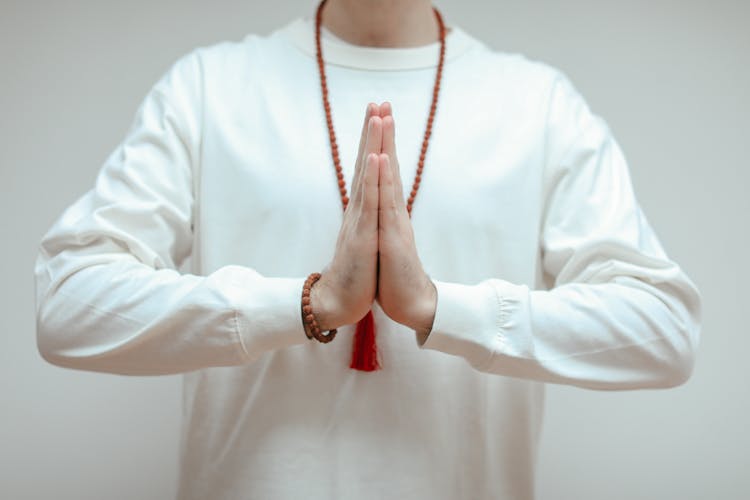 A Person In White Long Sleeve Doing Namaste Yoga