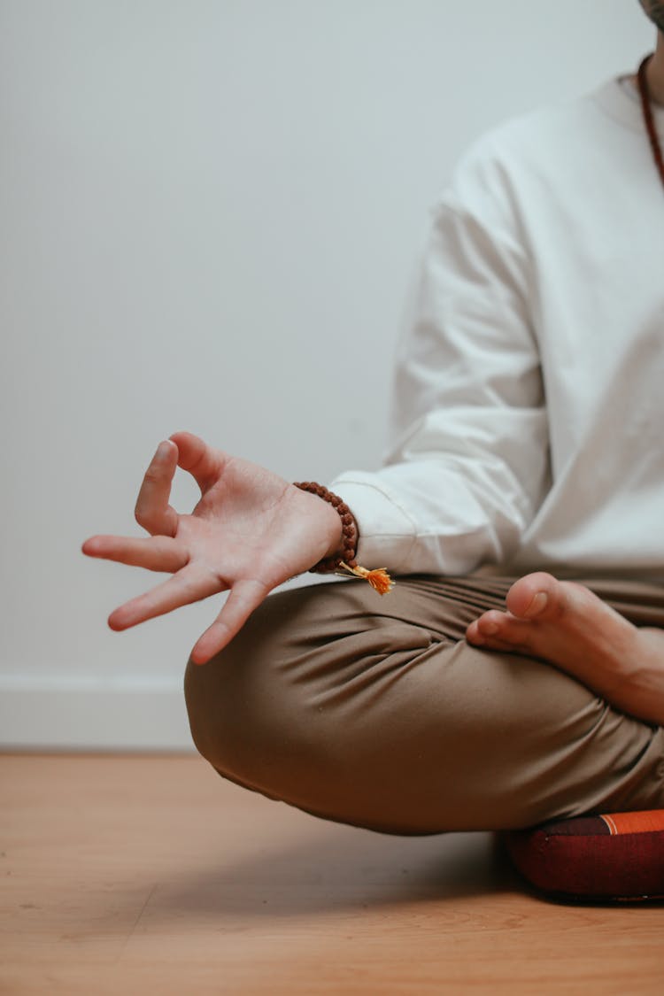 Man In White Long Sleeve Shirt And Brown Pants Sitting On Pillow Doing Yoga