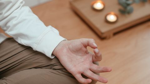 A serene close-up of a person meditating indoors with candles and a peaceful ambiance.