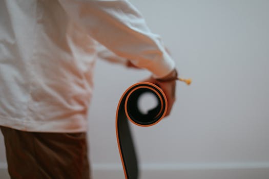 Close-up of a person rolling a yoga mat indoors, highlighting preparation for exercise.