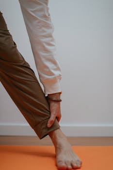 Minimalist close-up of a person's barefoot stretching during yoga on an orange mat indoors.