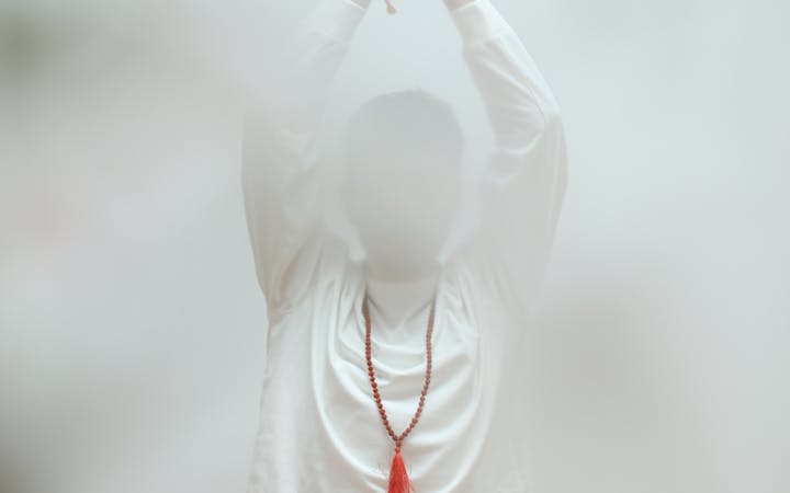 Person in lotus yoga pose practicing meditation indoors with soft focus.