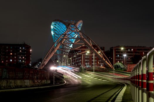 Long exposure capturing a modern bridge at night with light trails and vibrant lighting.
