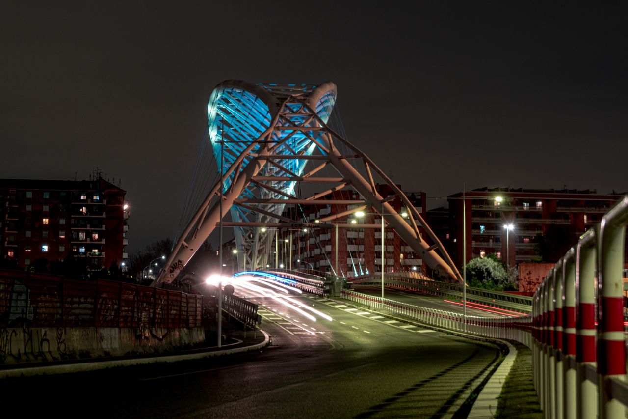 long exposure capturing a modern bridge at night with light trails and
