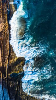 Stunning aerial photography capturing ocean waves crashing against a rugged coastline. Perfect for nature themes.