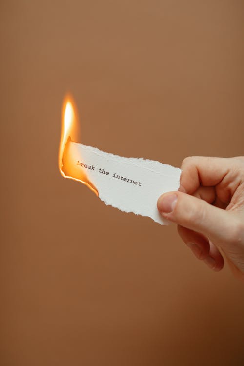 Hand Holding a Burning Torn Slip of Paper with Break the Internet Phrase 