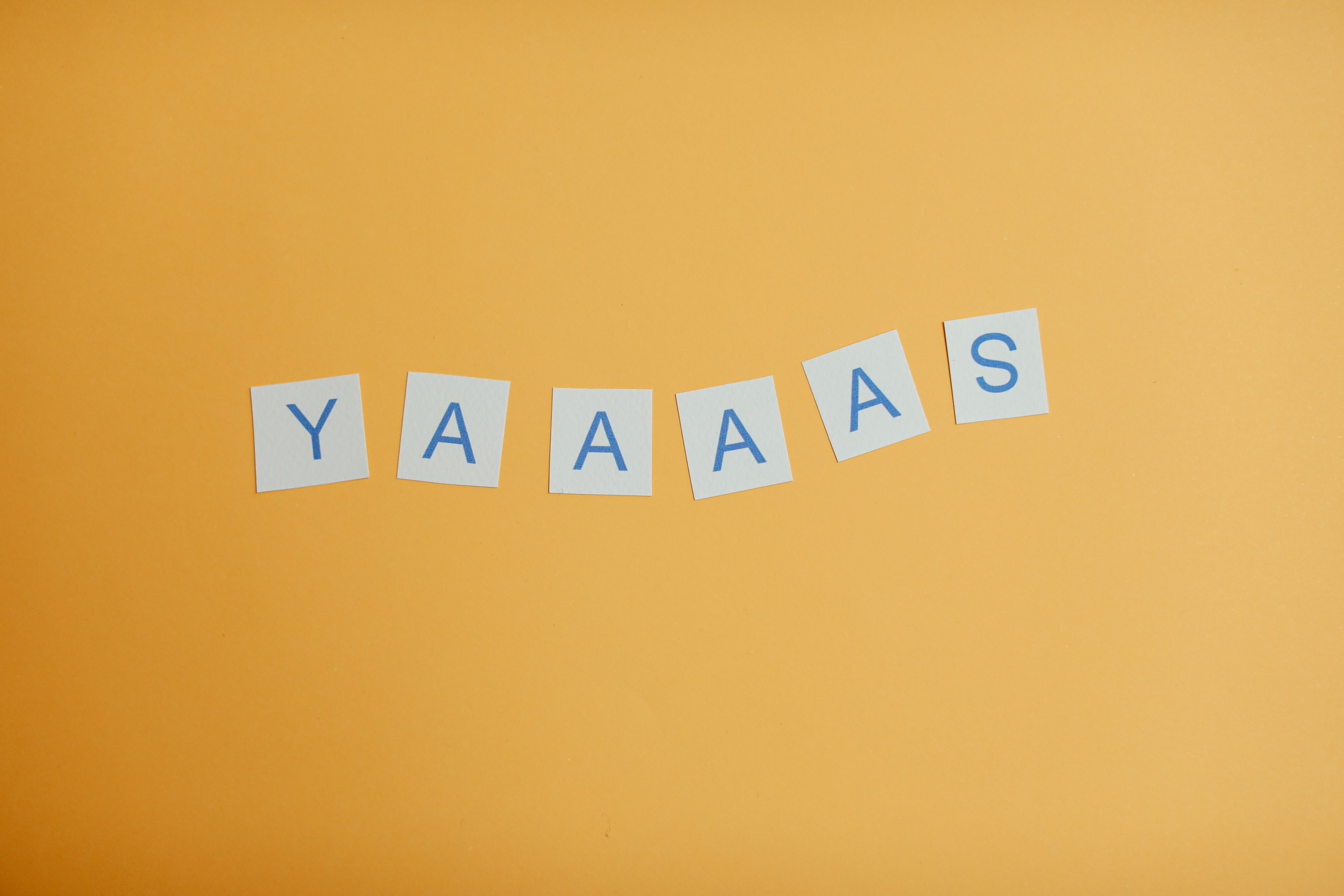 Creative arrangement of YAAAS letters on a vibrant yellow background. Perfect for motivational designs.
