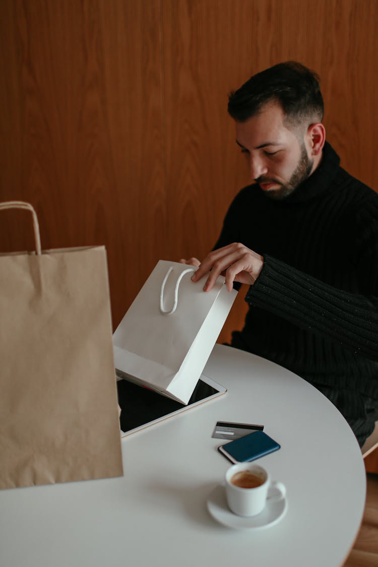 Young Guy Checking Purchases At Cafe