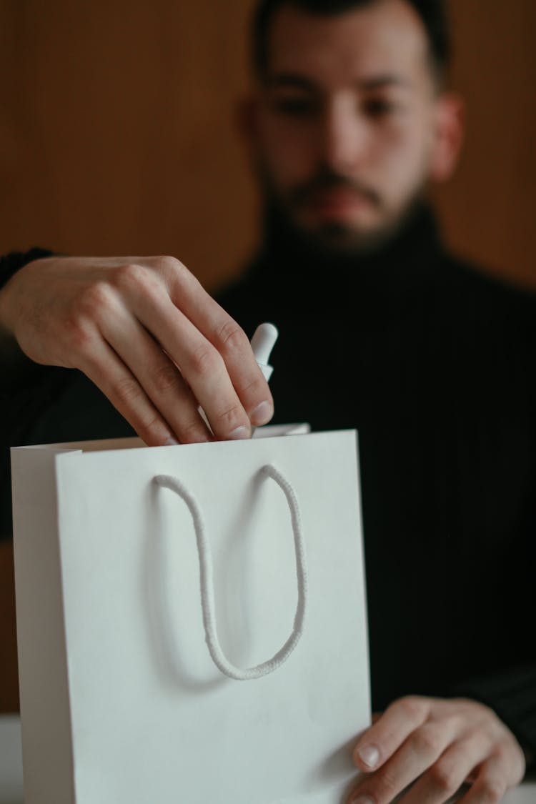 Concentrated Young Guy Unpacking Shopping Bag