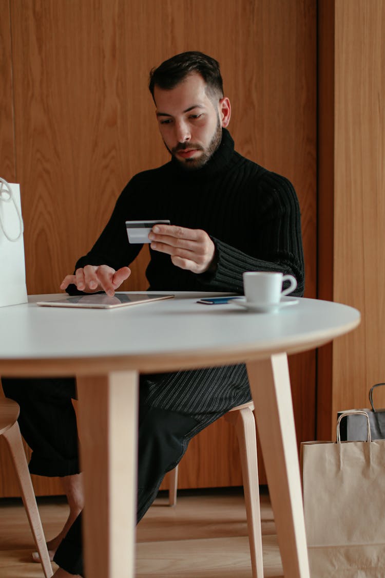 Confident Young Man Using Tablet And Doing Online Shopping At Home