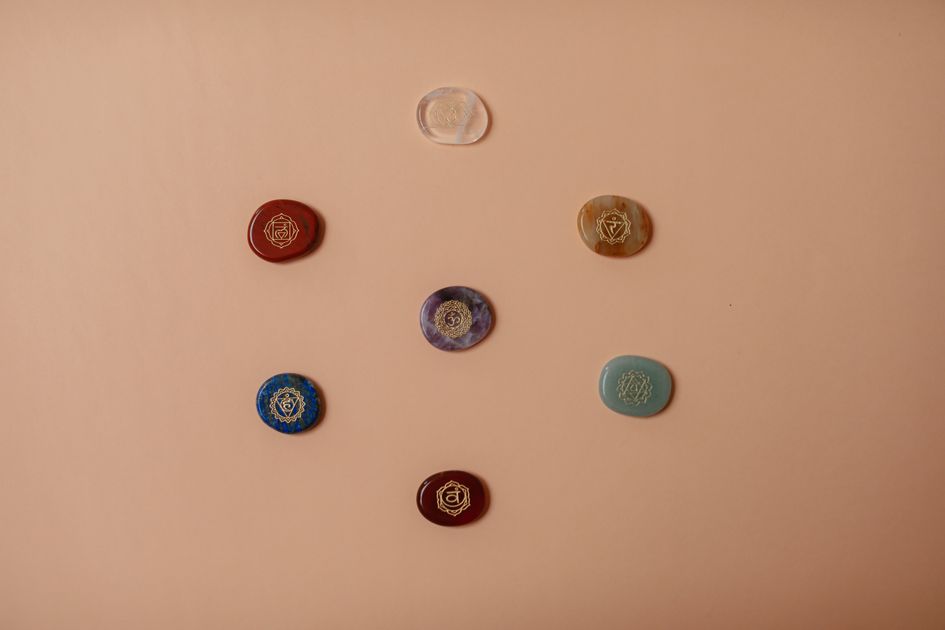 Flat lay of seven colorful chakra stones arranged in a row, representing the Destiny Matrix chakra energy line from root to crown