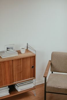 Cozy minimalist living room corner featuring a wooden cabinet and armchair with neutral tones.