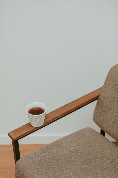 Cup resting on the arm of a linen chair by Cup of Couple on Pexels