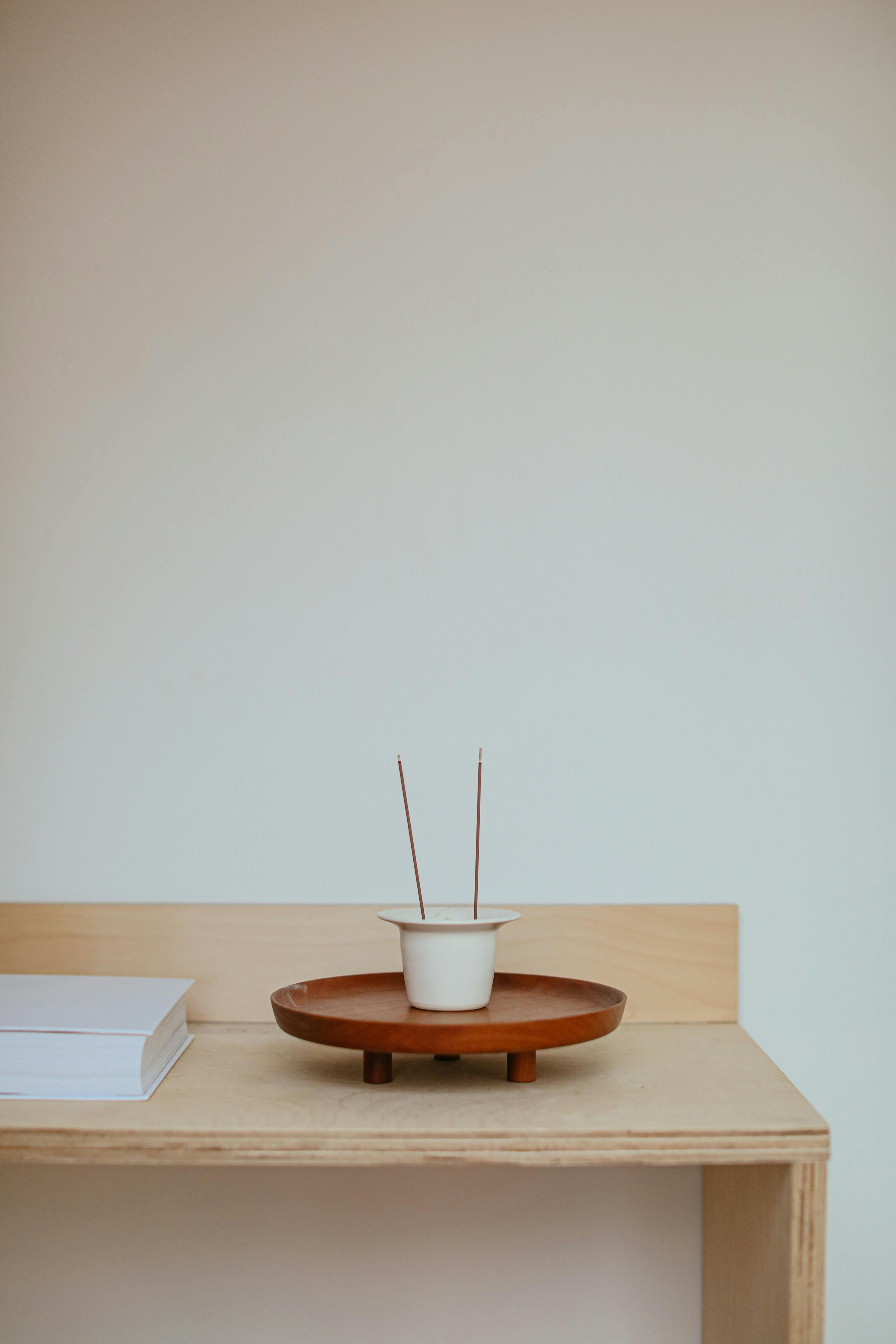 Minimalist incense holder with sticks on a wooden shelf, offering a serene ambiance.