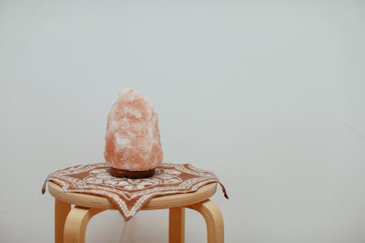 A serene image of a Himalayan salt lamp on a wooden stool, perfect for mindfulness and ambiance.