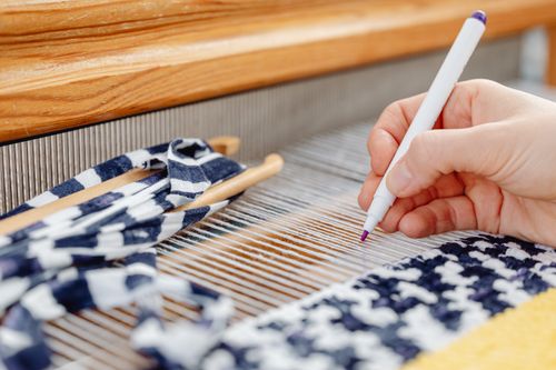 Close-up of a weaver's hand working with a loom