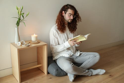 Man Reading a Book While Sitting on the Floor