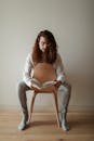 A Man Sitting on a Wooden Chair Holding a Book