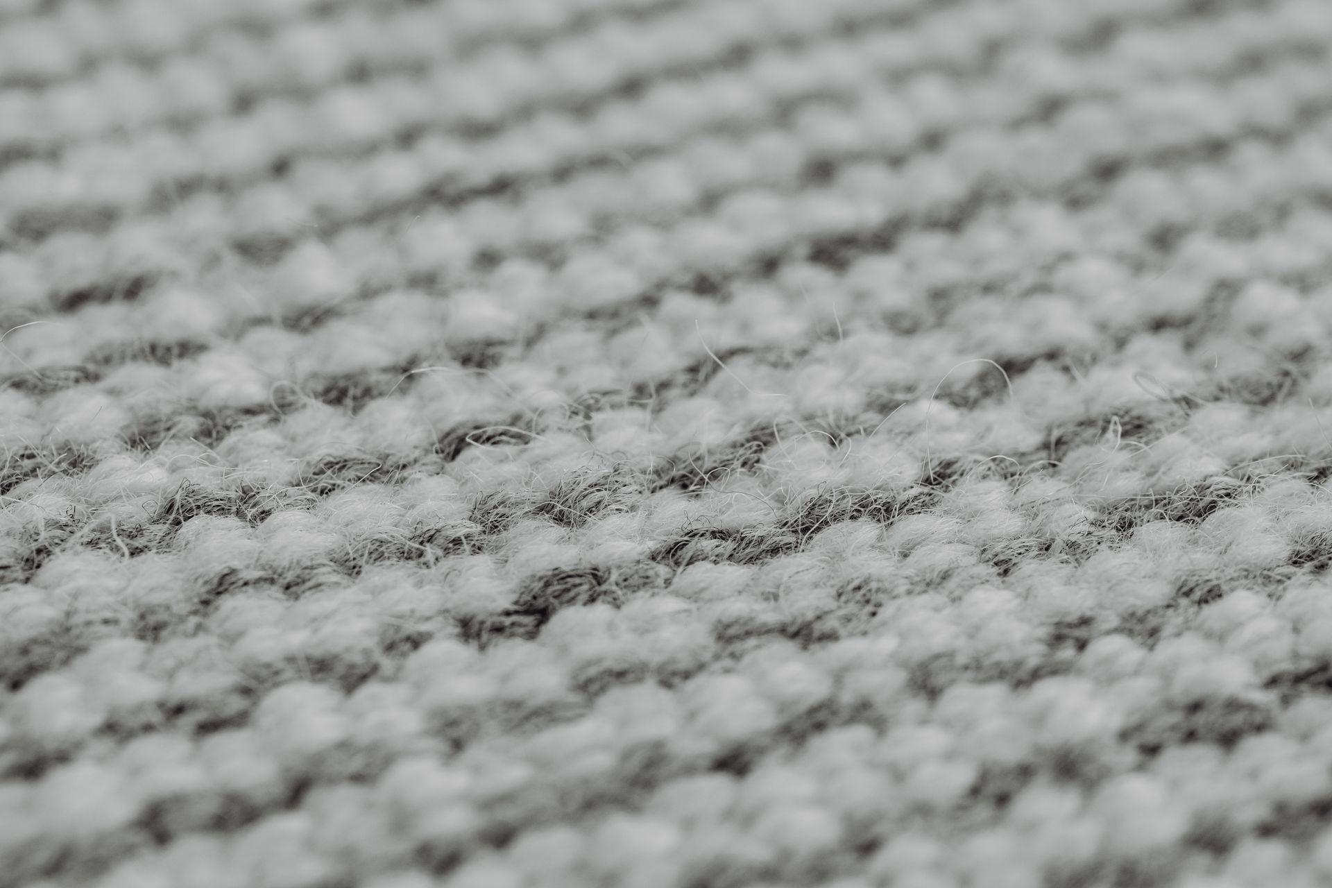 Detailed view of a grey, handmade wool textile showing its knit pattern and texture.