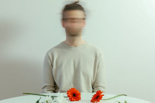 A Person Sitting Near the Table with Flowers