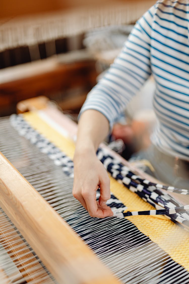 A Person Inserting Fabric In The Loom