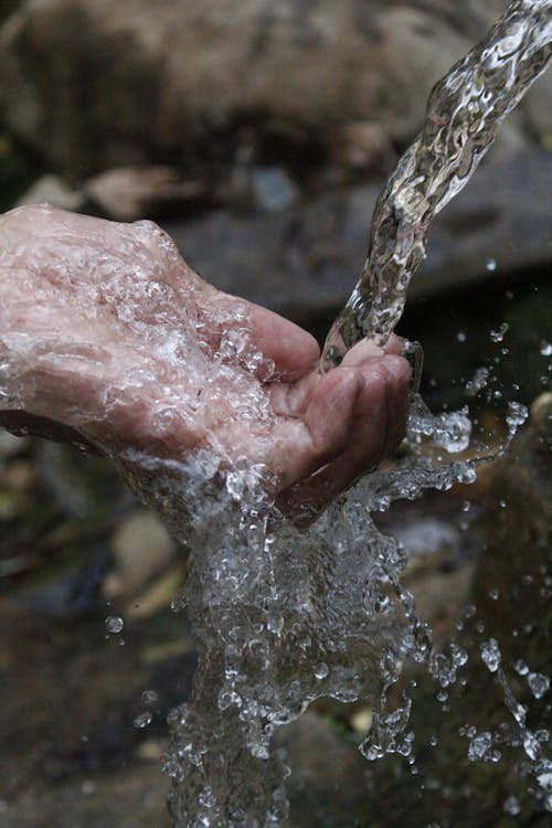 Image of a hand touching a flowing water in a close up perspective