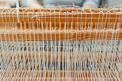 Detailed close-up of a wooden loom with white threads, showcasing traditional weaving.