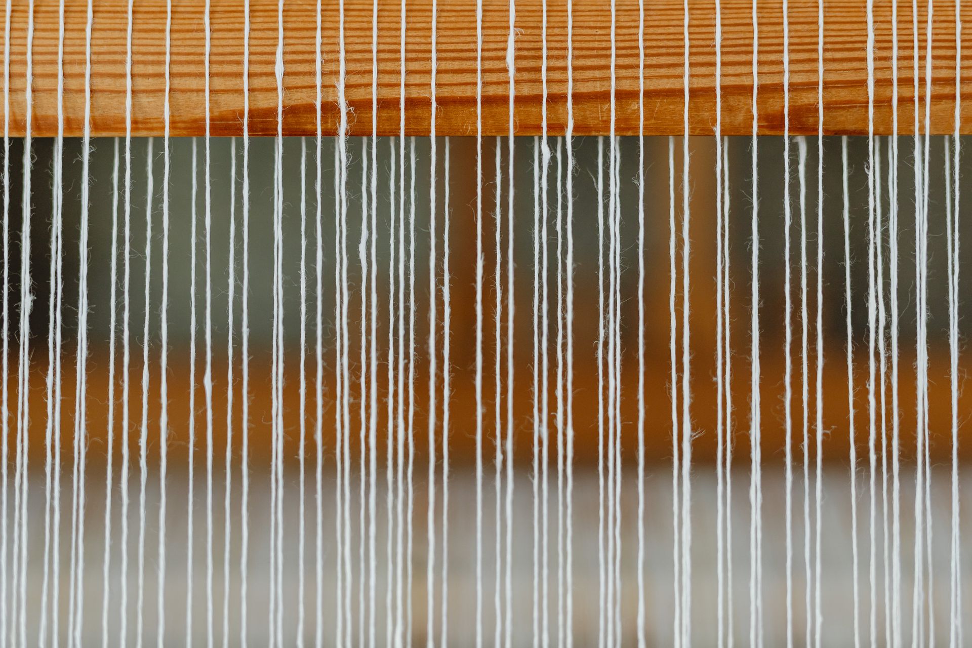 Detailed view of a loom with white yarn threads, showcasing textile weaving craftsmanship.