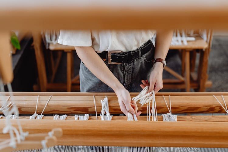 Woman Weaving With Threads On Wooden Machine