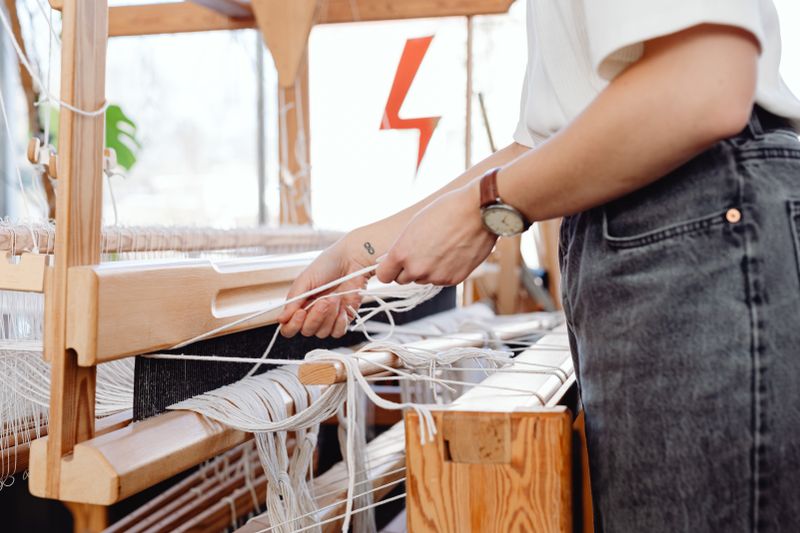A woman weaving on a wooden loom, showcasing traditional craft techniques.