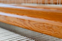 Detailed close-up image of a traditional wooden loom with white threads in focus.
