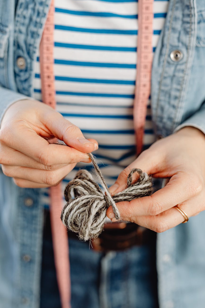 Close-up of hands working with yarn and measuring tape in a crafting setup.