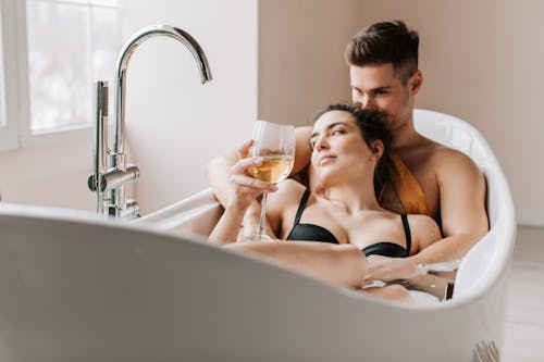 A Couple Soaked in the Bathtub While Drinking Wine