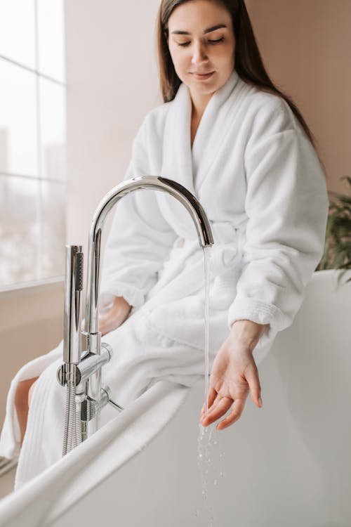 Woman in White Robe Sitting on the Bathtub