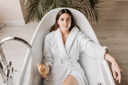 A Woman Lying in the Bathtub Holding a Glass of Wine