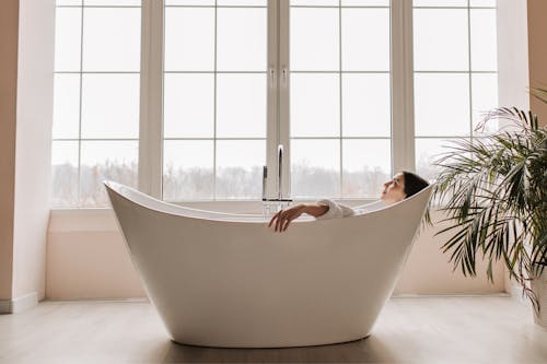 A Woman Lying in the Bathtub Near the Glass Window