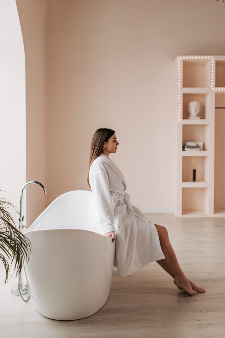 Woman In White Robe Sitting Inside The Bathroom