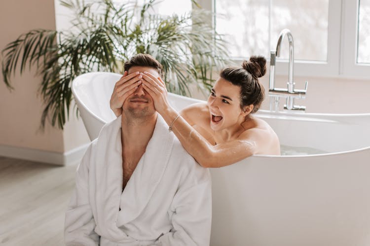 Man Sitting Beside A Woman Taking A Bath