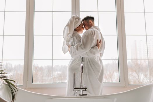 Woman in White Long Sleeve Shirt Standing in Front of Window