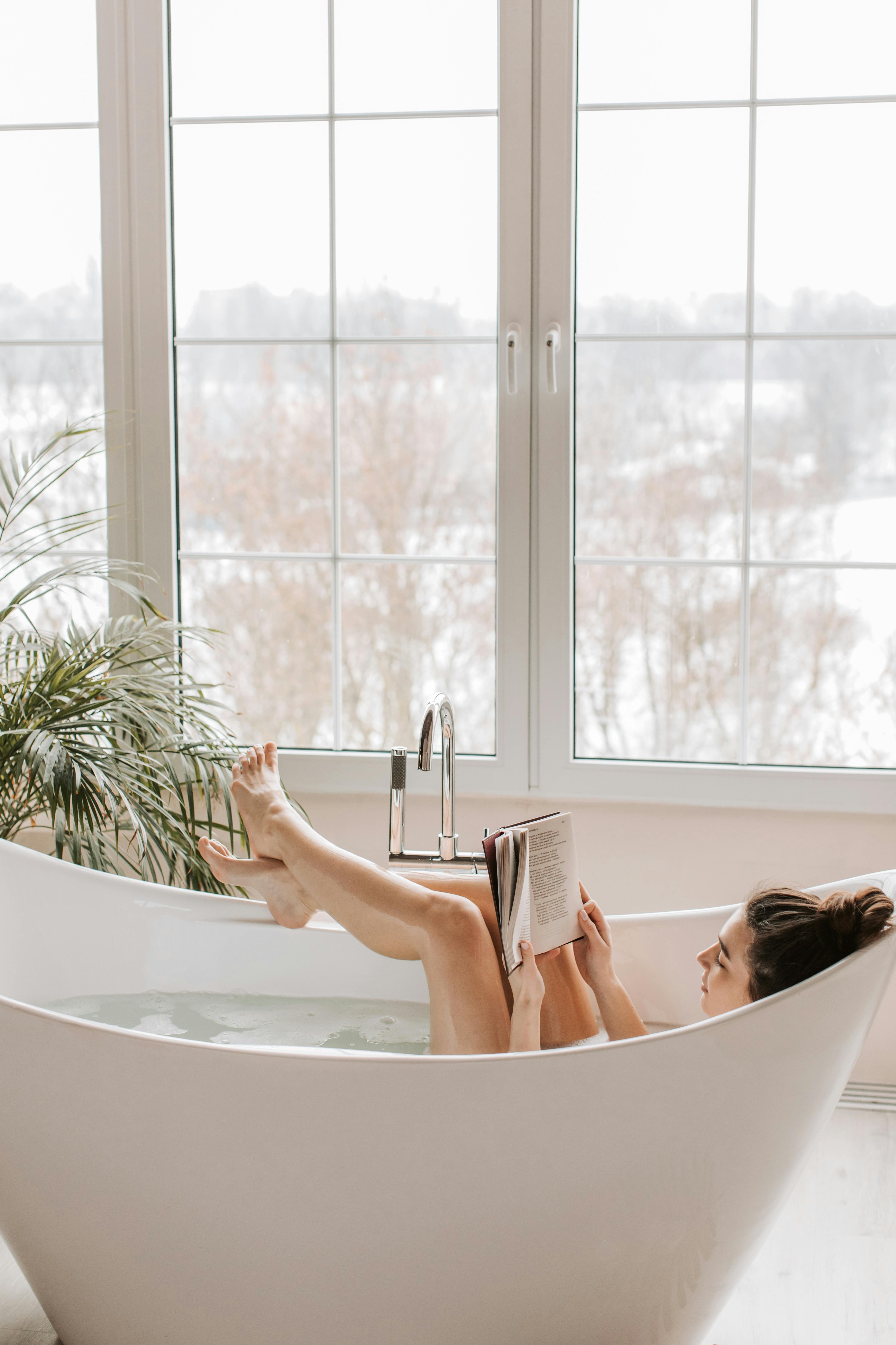 a woman reading a book in a bathtub