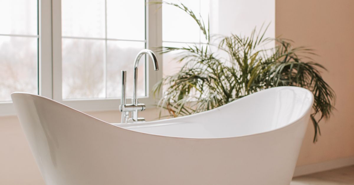 Banheiro com janela e plantas Banheira branca ao lado da janela em banheiro minimalista com plantas