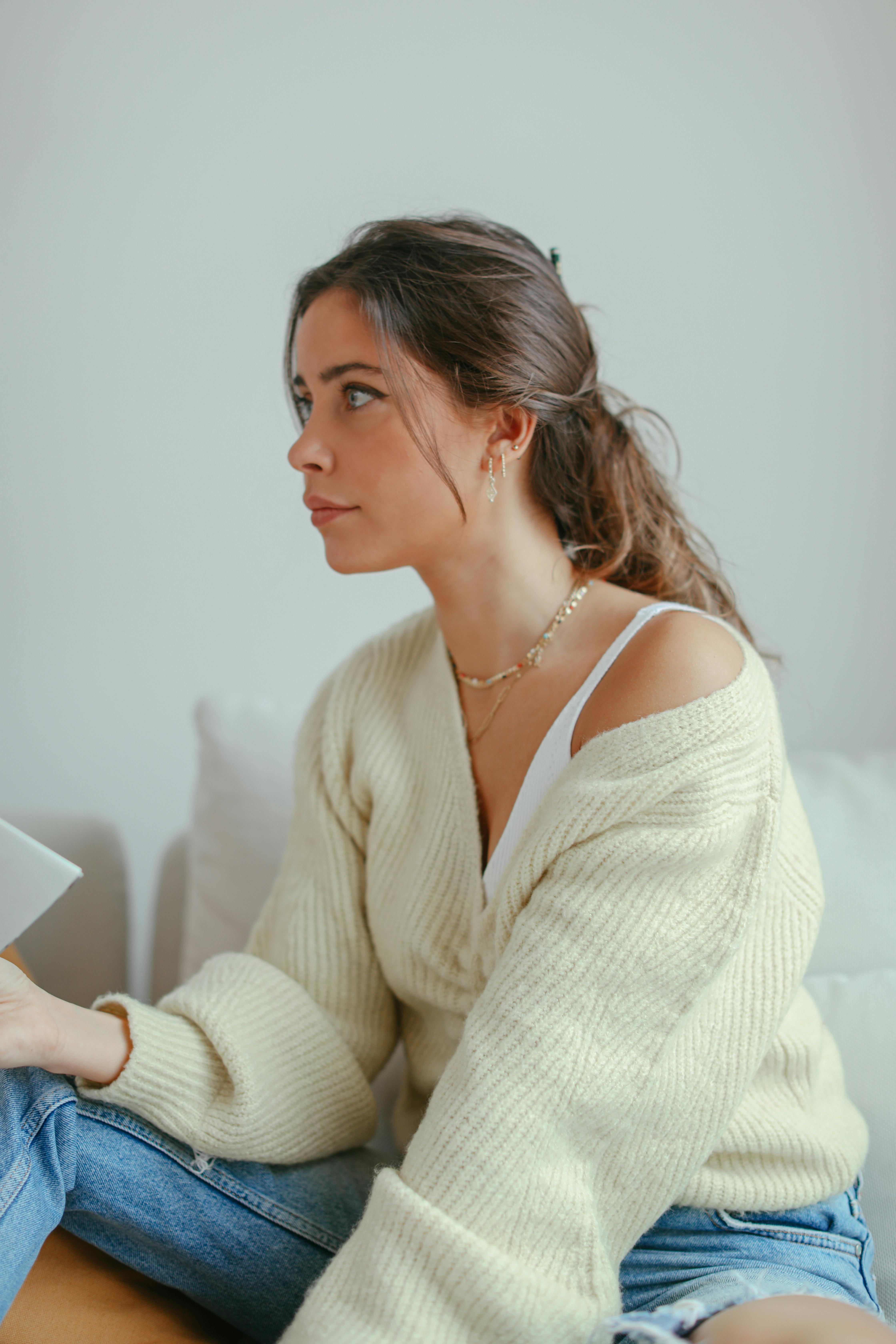 Woman in a cozy cardigan enjoying a quiet moment indoors with a stylish and relaxed vibe.