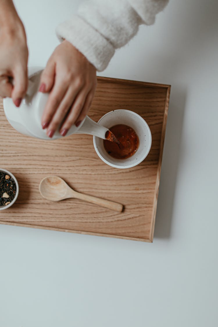 Person Pouring Tea On A White Cup