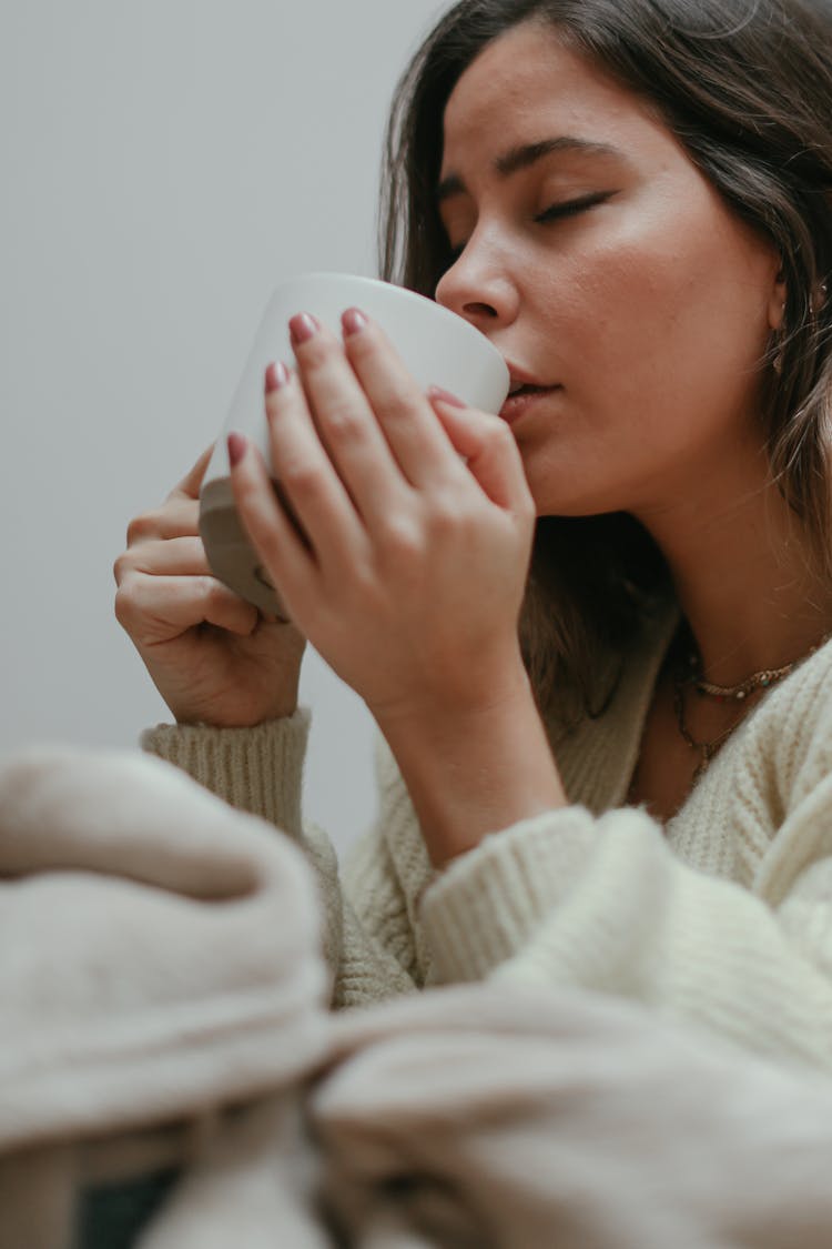 A Woman Sipping From A Mug 